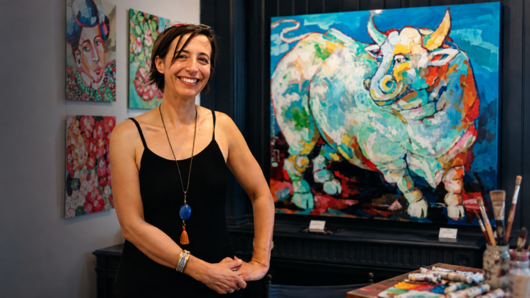 French contemporary artist Julie Buffet in her studio surrounded by her colourful figurative paintings and artworks.